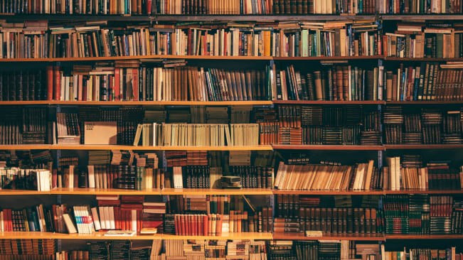 A packed bookshelf that stretches from floor to ceiling
